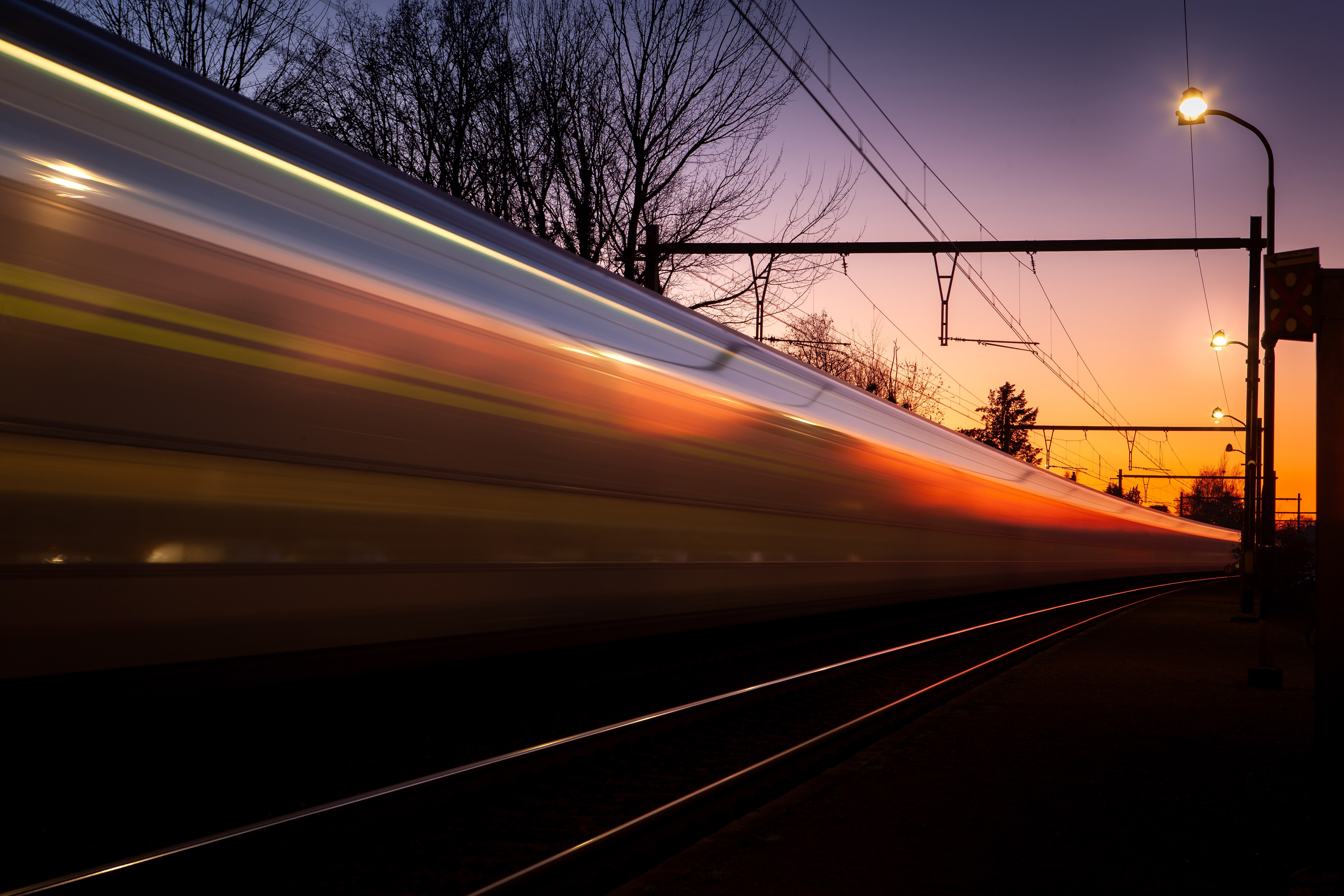 A blurred train zooming past the camera at sunset