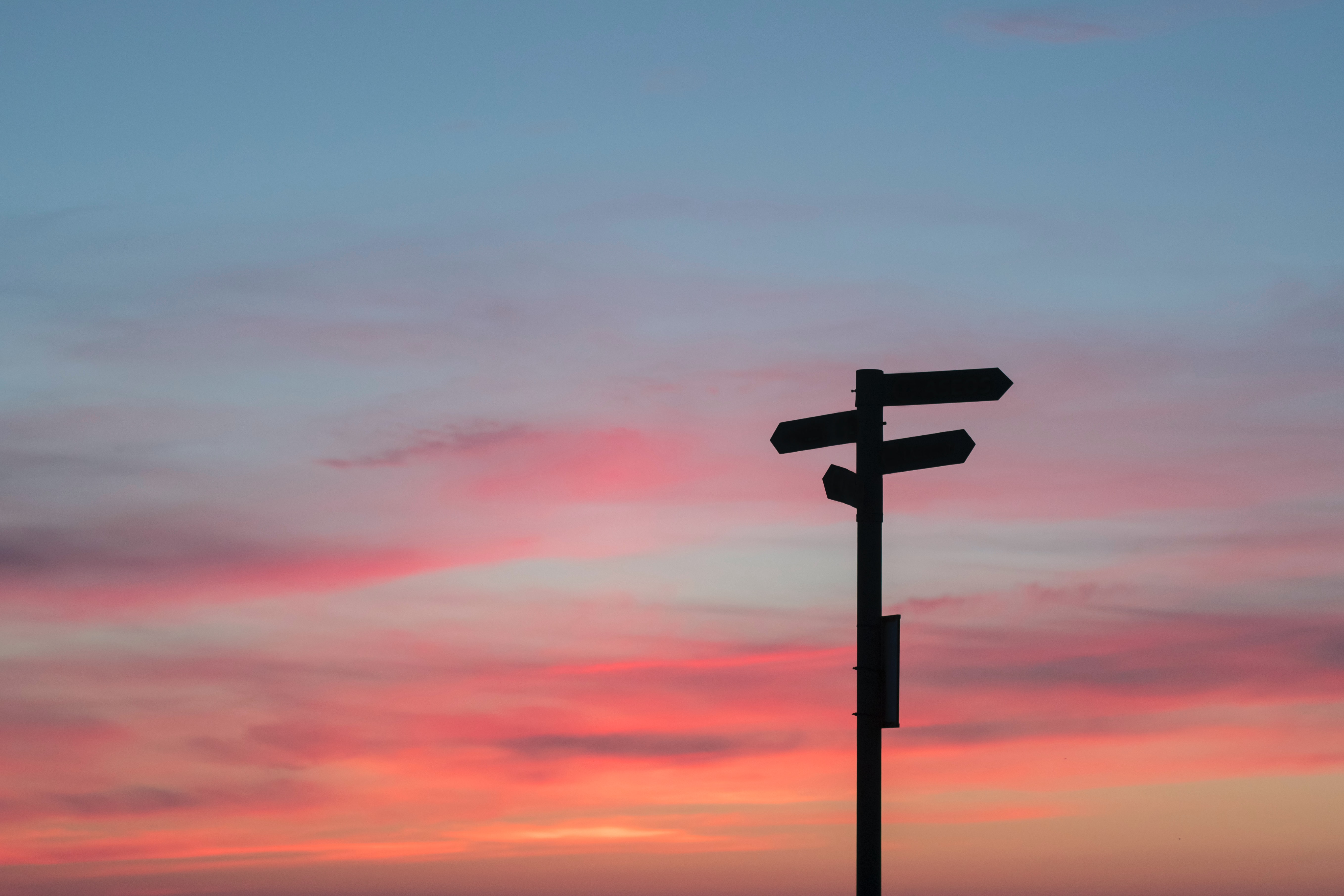 A silhouette of a directional sign at sunset