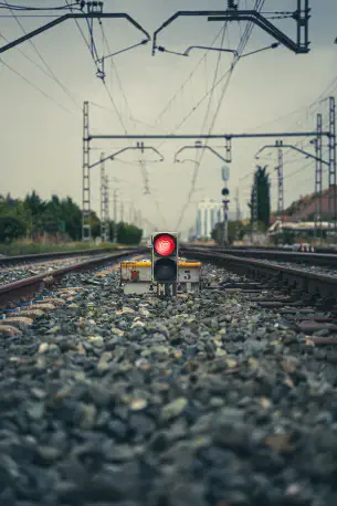 A red stoplight activated along train tracks.