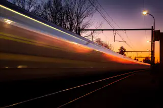 A blurred train zooming past the camera at sunset.