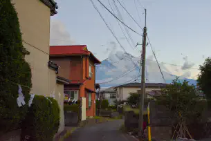 A small neighborhood in Japan. Mount Fuji can be seen in the background covered in whispy clouds.